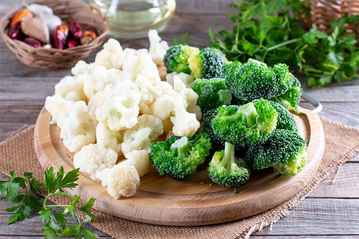 Raw broccoli and cauliflower florets arranged on a plate with a side of dipping sauce