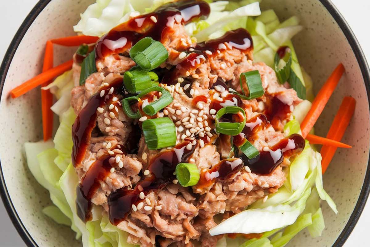 A bowl of reheated egg roll in a bowl with ground pork, cabbage, and carrots, ready to be served.