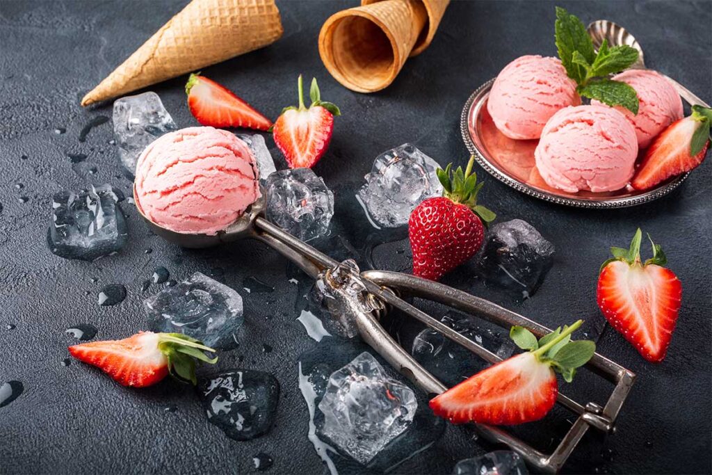 Mixing fresh strawberries into an ice cream base to prevent icy texture in homemade strawberry ice cream