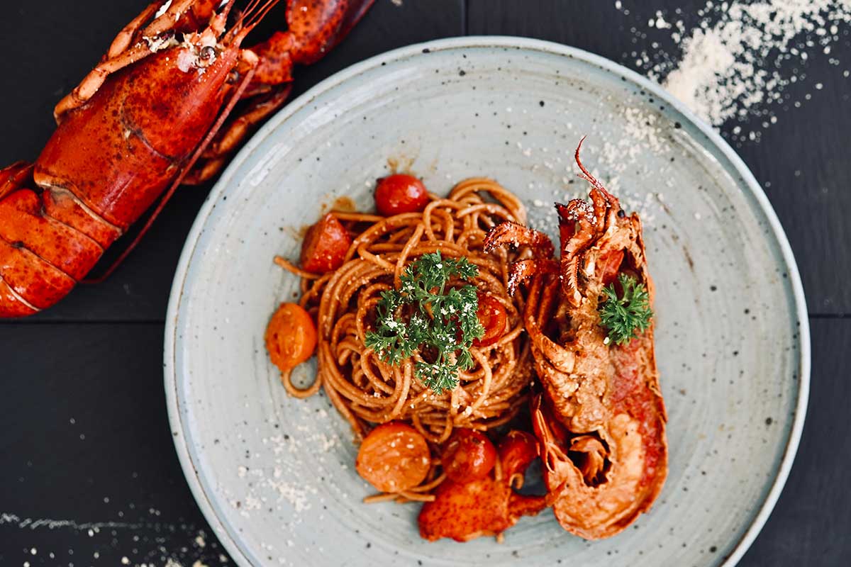 Plate recipe of lobster pasta garnished with fresh herbs