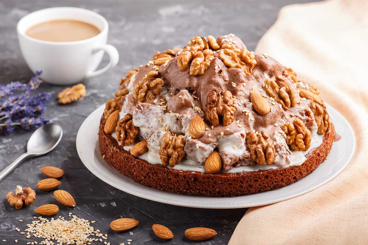 A freshly baked almond nut cake topped with flaked almonds and dusted with powdered sugar.