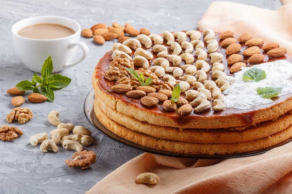 A selection of nuts including almonds, walnuts, and pecans placed beside a slice of cake.