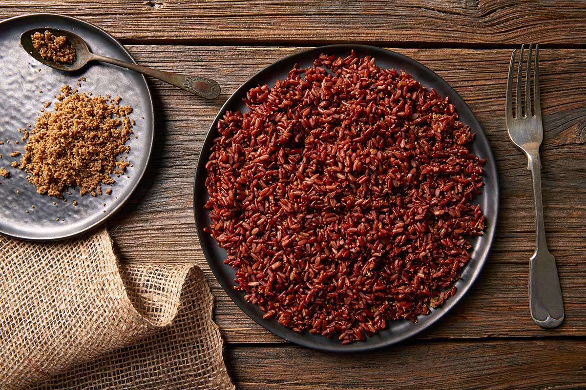 Cooking red rice in a skillet with tomato, garlic, and onions