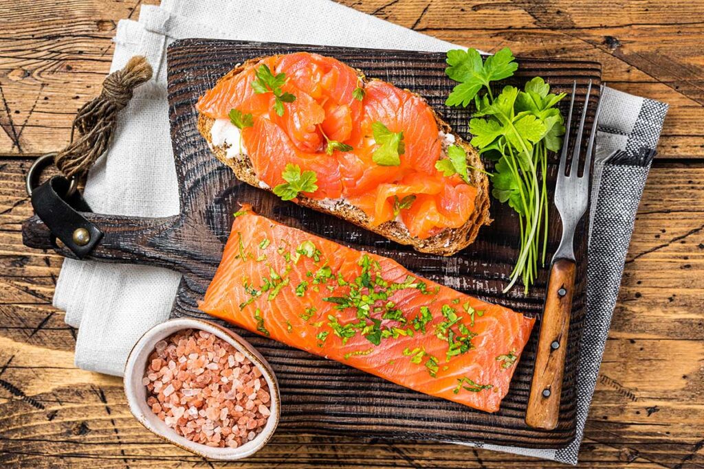 A plate of smoked salmon with fresh greens and lemon slices, showcasing a healthy and nutritious meal.