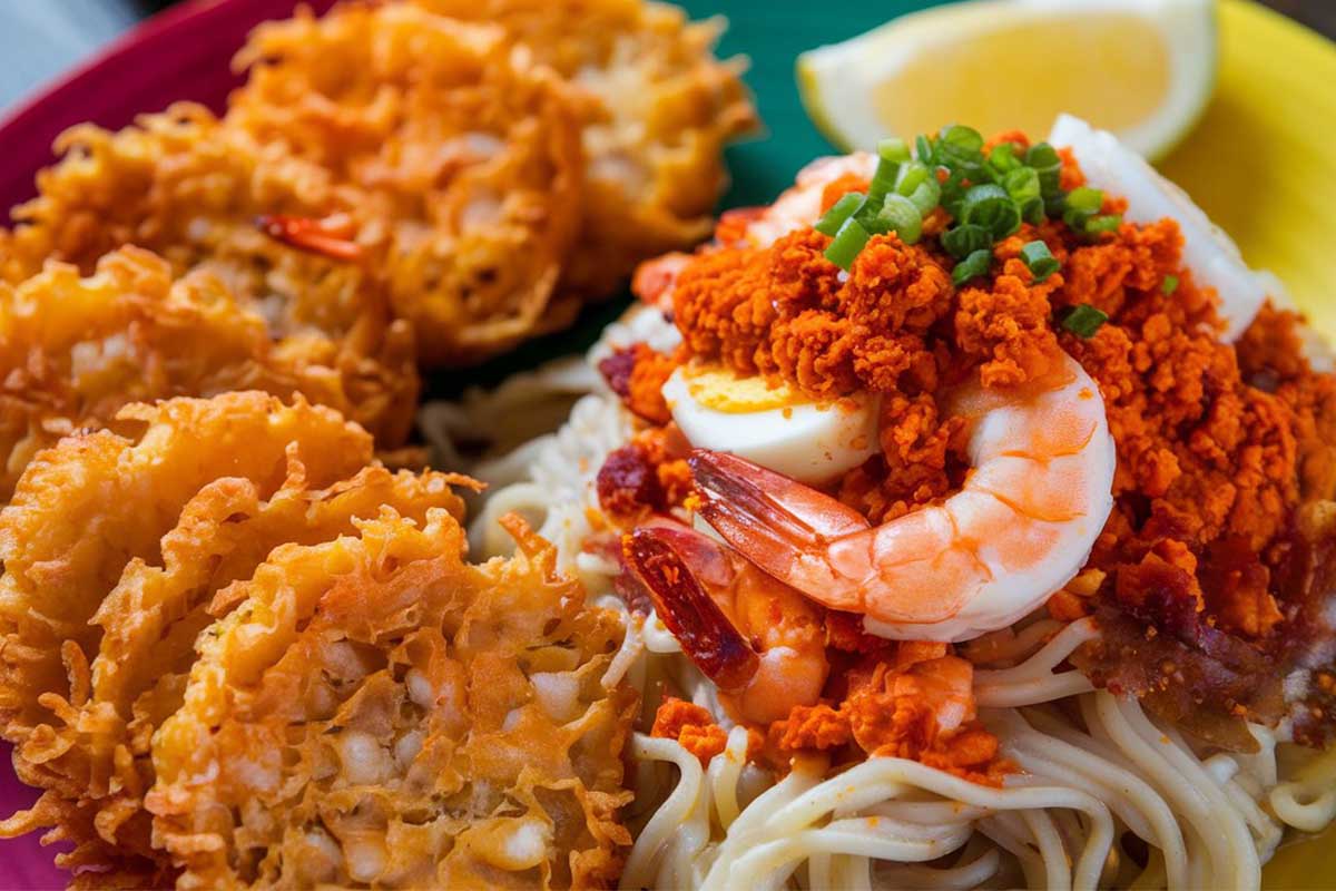 ALT Text: A plate of crispy Sweet Potato Ukoy served with savory Palabok noodles garnished with green onions and lemon wedges.